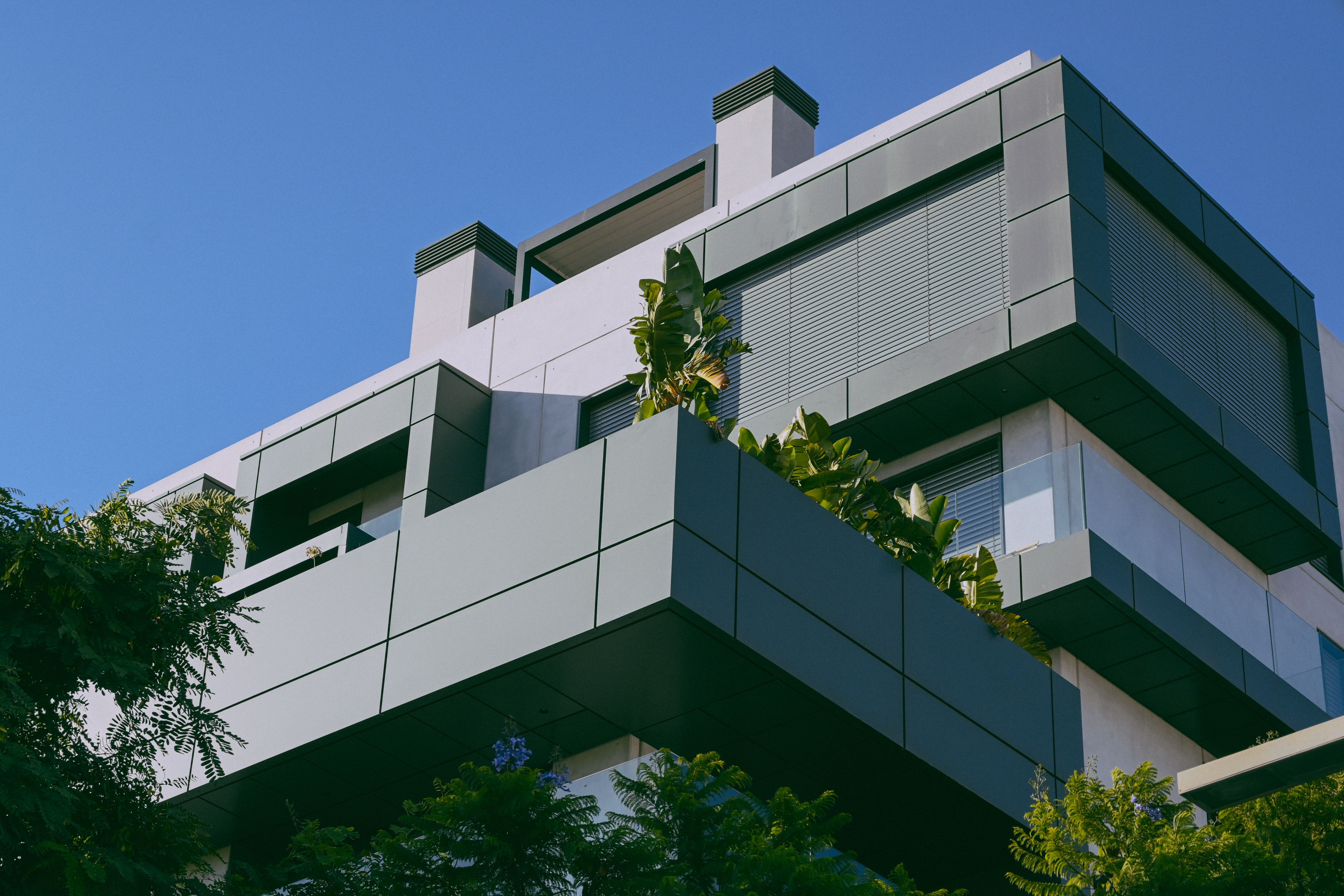 Modern residence exterior with tiered concrete balconies and lush plantings